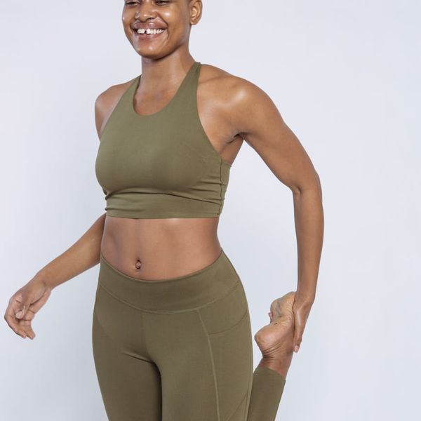 Woman smiling peacefully during a light stretching exercise in a bright room.